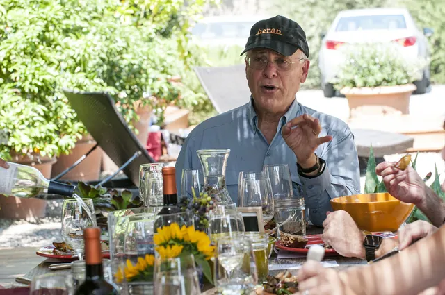 Randle Johnson speaking at an outdoor table set with wine glasses