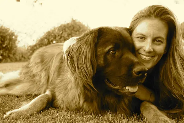 Sepia photo of Holly smiling beside Hank the dog